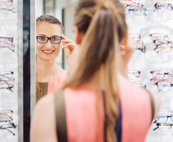 Young woman trying fashionable glasses in optometrist store Young woman trying fashionable glasses in optometrist store