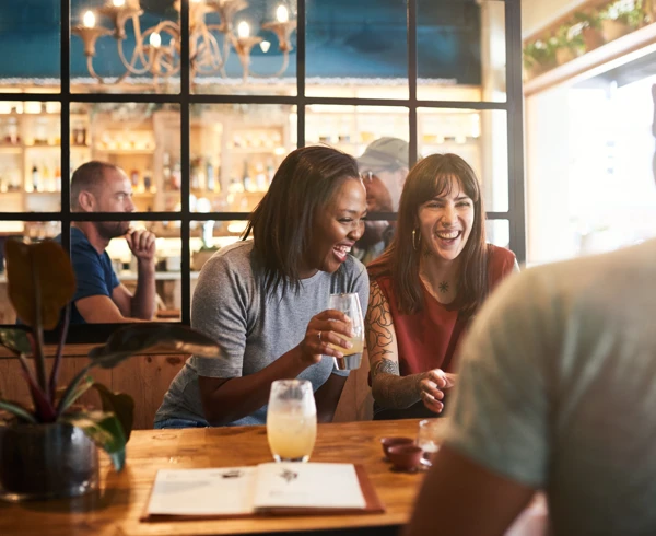 Diverse young friends laughing over drinks together in a bar Diverse young friends laughing over drinks together in a bar